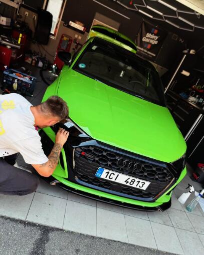 Jasně zelené wrapnuté Audi RS v dílně při práci na masce